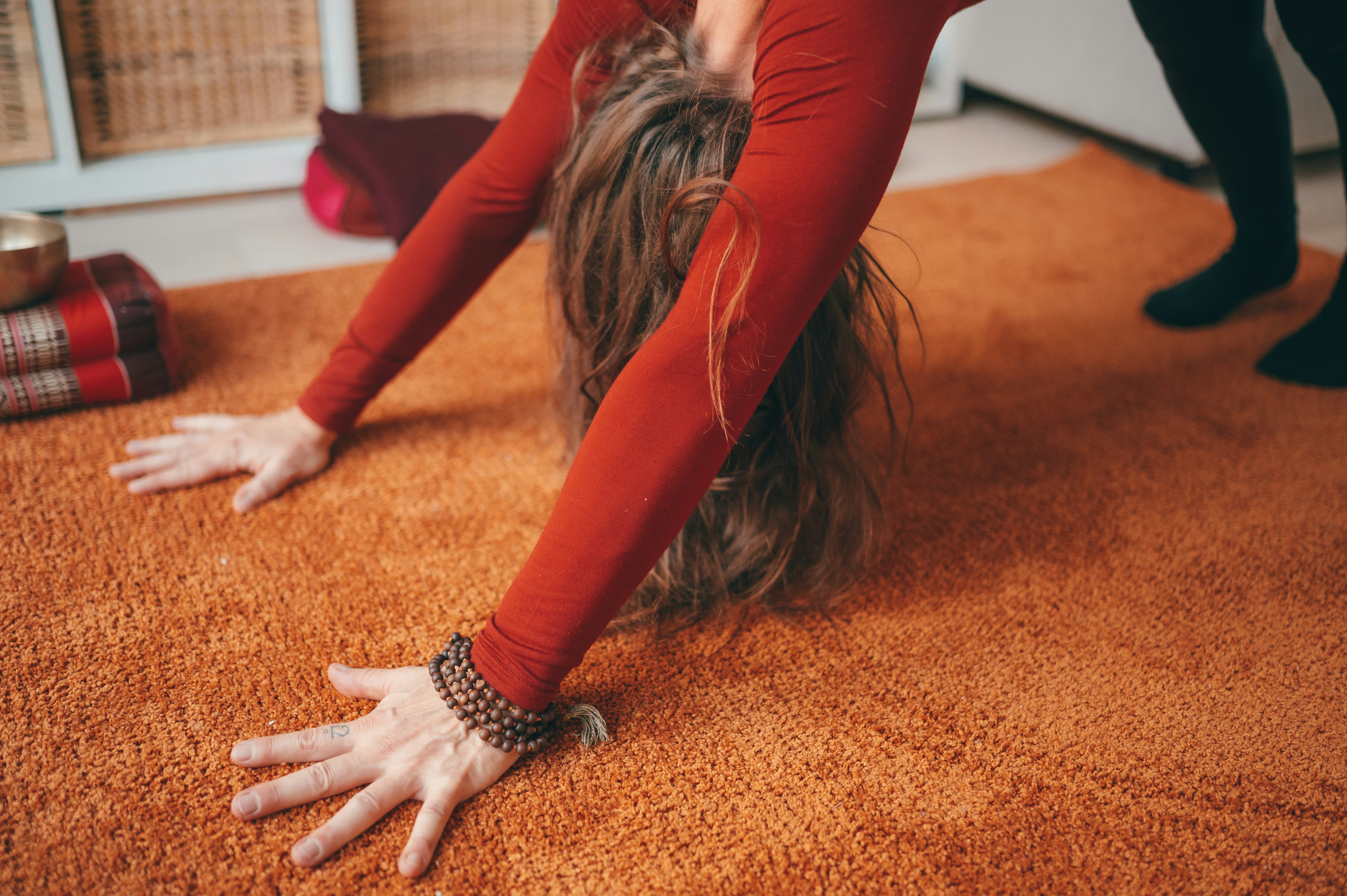 woman in red long sleeve shirt and red pants lying on brown carpet